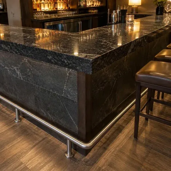 Corner of a stone bar countertop with a brass footrail in a Baltimore restaurant