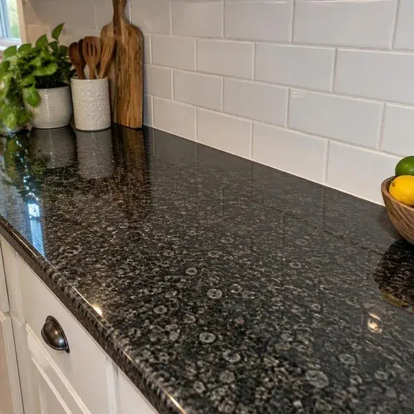 Polished black granite countertop meeting a tiled backsplash, showing the deep finish of a granite installation