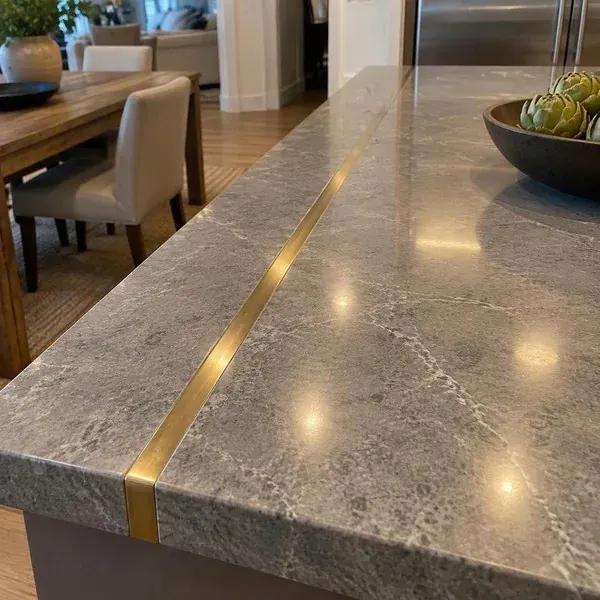Thin brass metal inlay strip set flush into a polished stone countertop surface