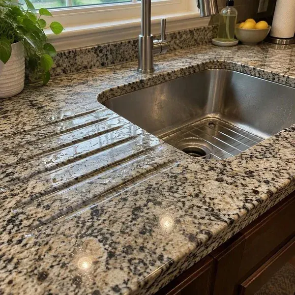 Drainboard grooves cut beside an undermount sink in a stone countertop