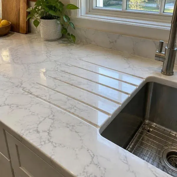 Drainboard grooves in white marble Drainboard grooves cut into a white marble countertop beside a kitchen sink