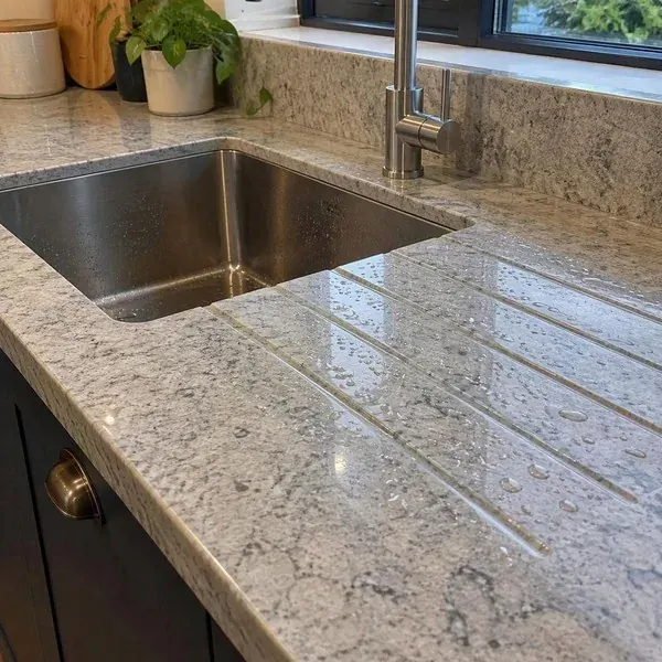Granite drainboard grooves with water droplets Angled drainboard grooves in a granite countertop with water droplets running toward the sink