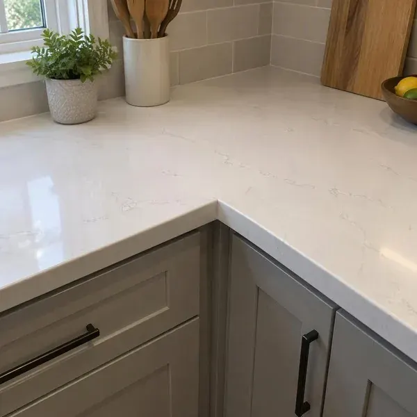 Seam at the inside corner of an L-shaped stone countertop over white cabinets