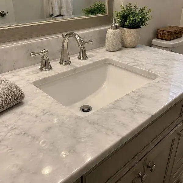 White marble vanity top around a faucet base, where etching and water marks call for marble repair in Baltimore
