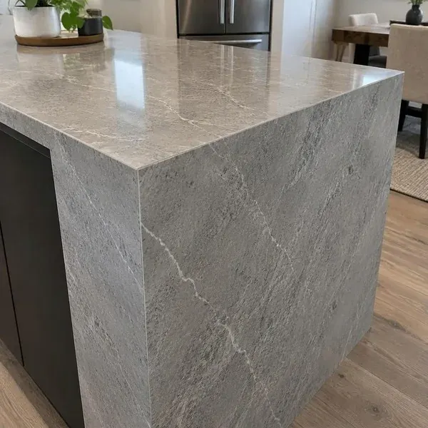 Close-up of a tight mitered waterfall edge seam where a countertop meets its side panel