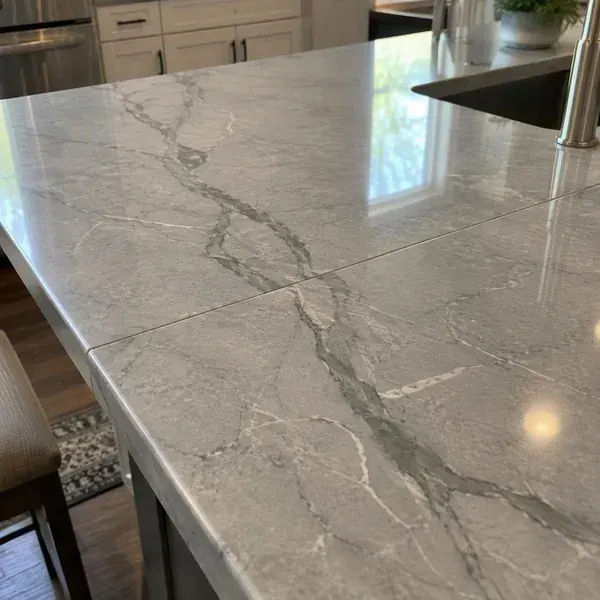 Close-up of a vein-matched seam in white quartz where the gray veining continues across the joint